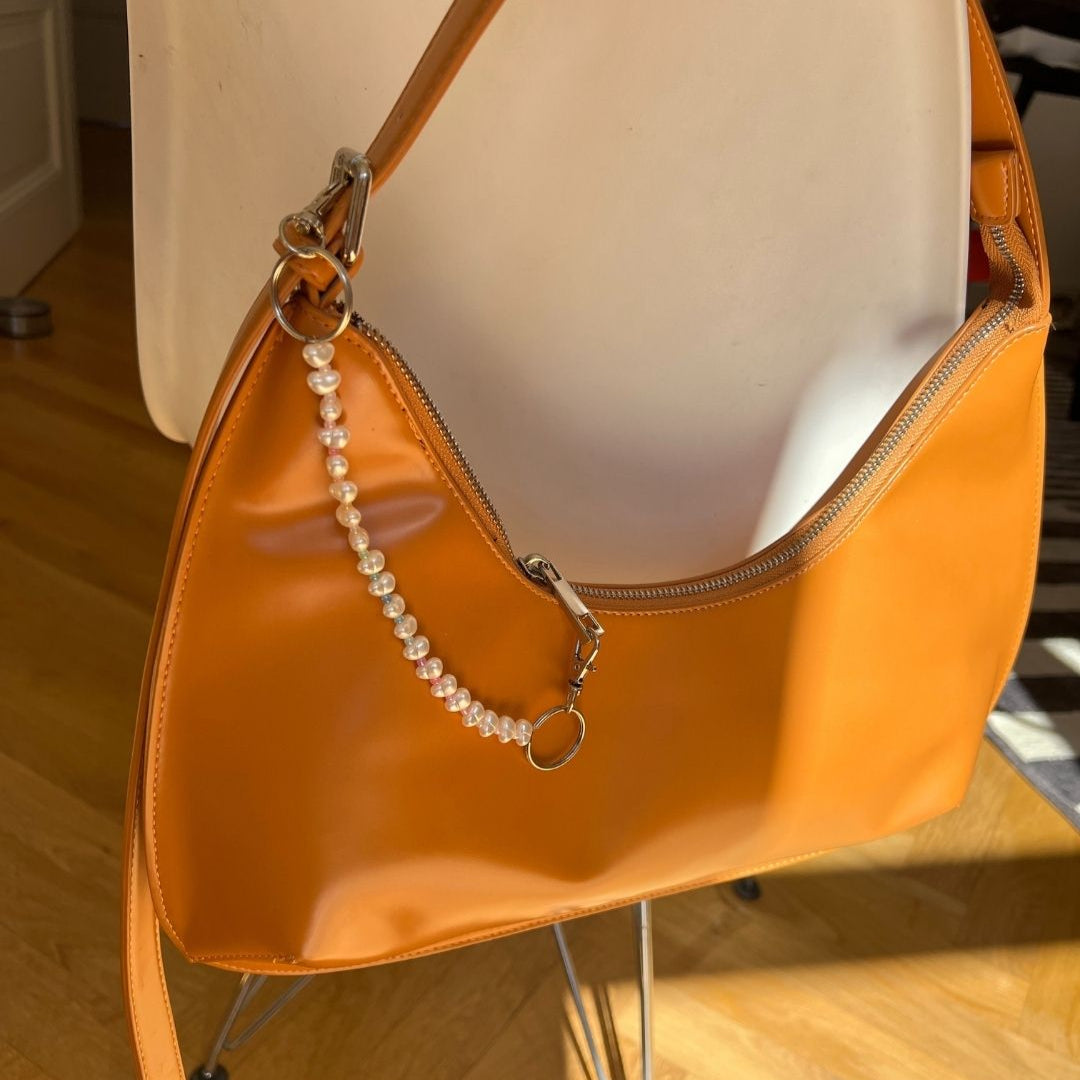 Rainbow bag charm on an orange handbag